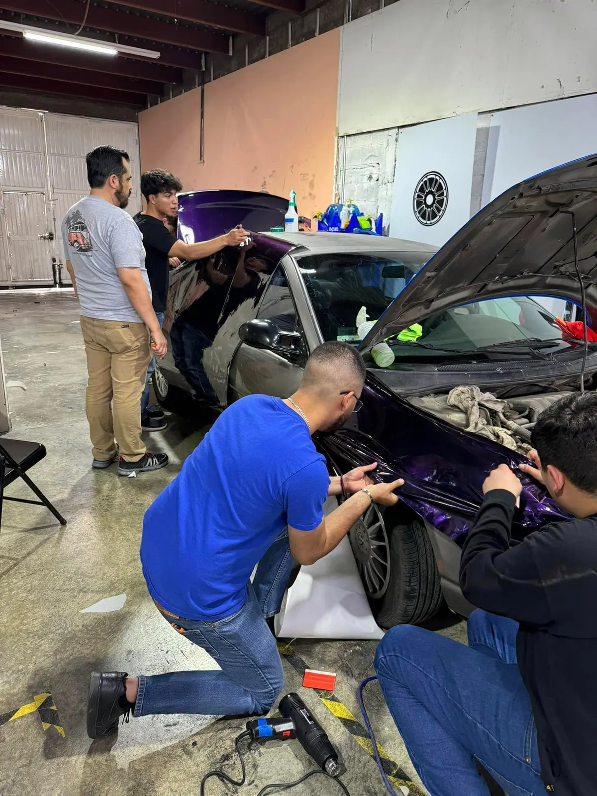 Alumnos instalando wrap en un auto durante el curso