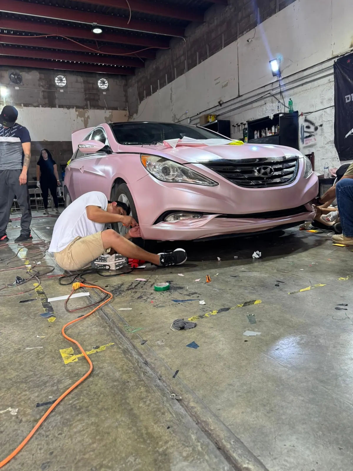 Alumnos instalando wrap rosa en un Hyundai Sonata durante el curso