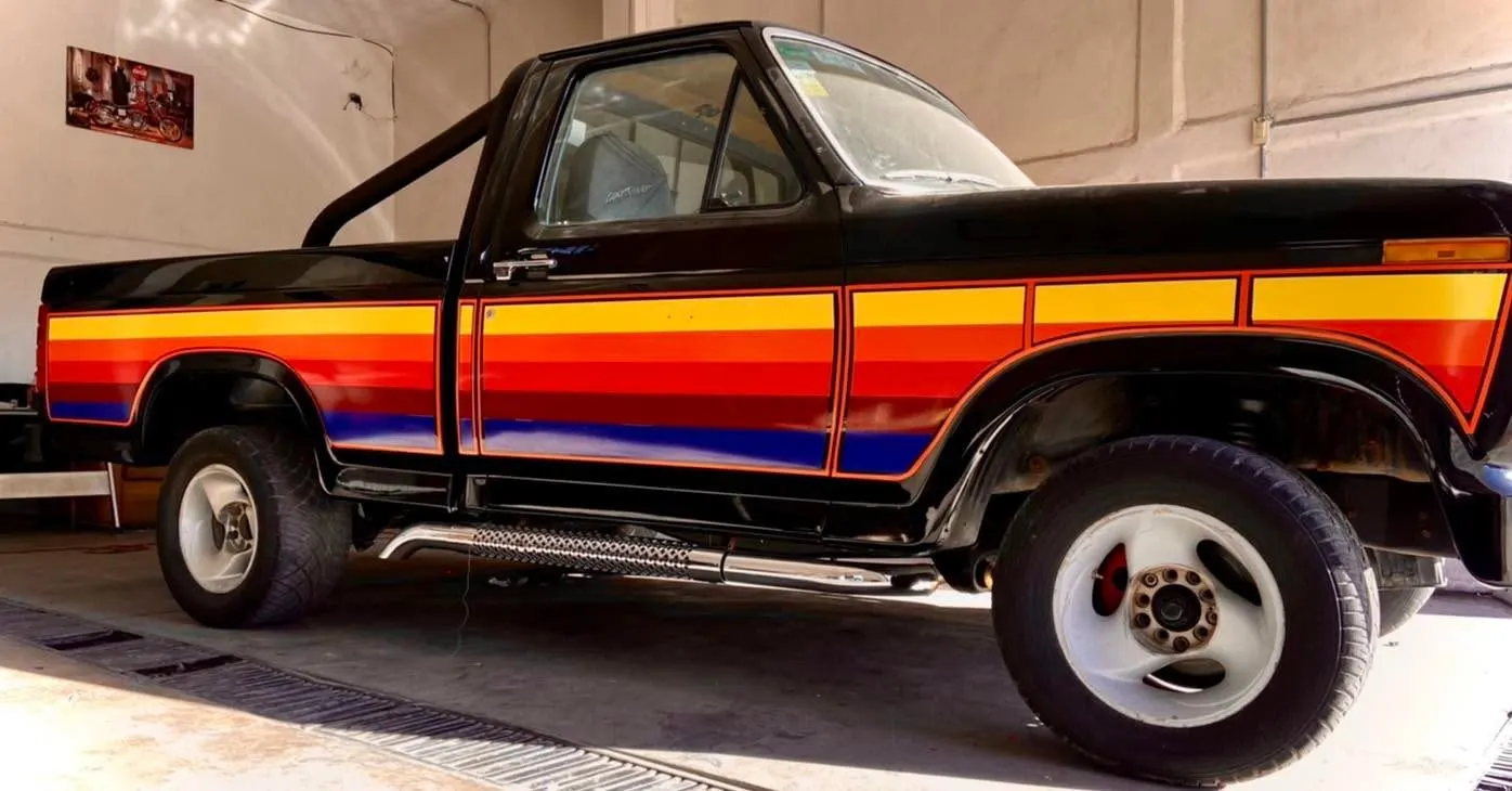 Pickup clásica negra con franjas retro en naranja, amarillo y rojo