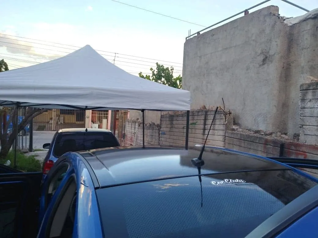 Auto azul con techo en vinil negro, bajo la carpa