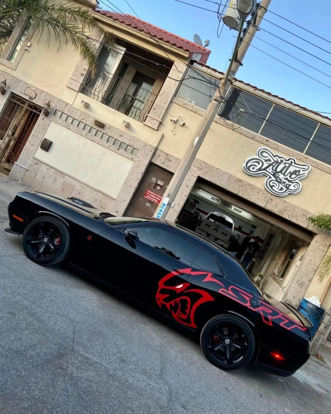 Dodge Challenger negro con gráfico SRT rojo en el costado, frente al segundo taller