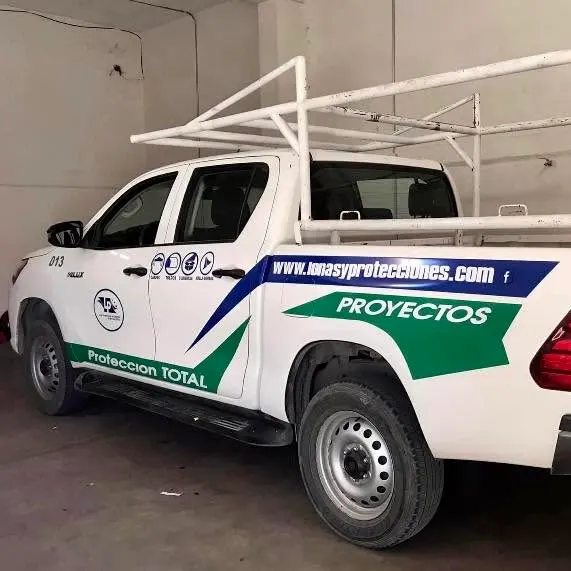 Pickup blanca rotulada con franjas azul y verde y sitio web de la empresa