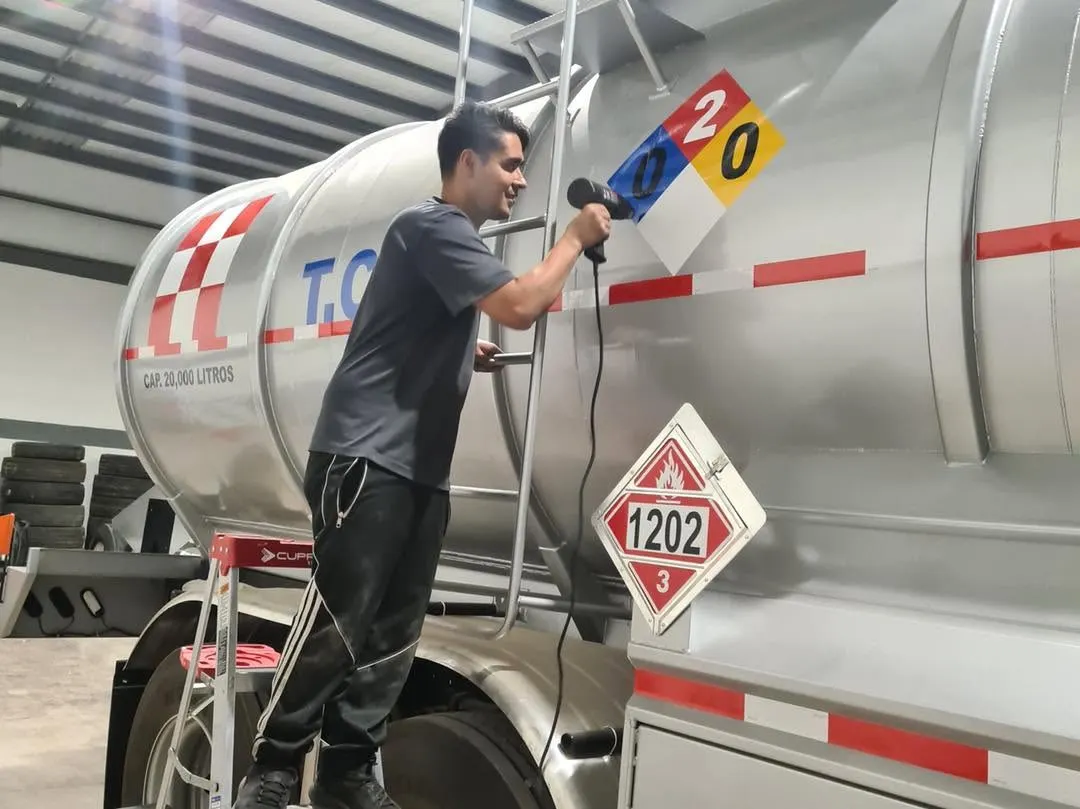 Instalador colocando vinil sobre el tanque de una pipa de gas