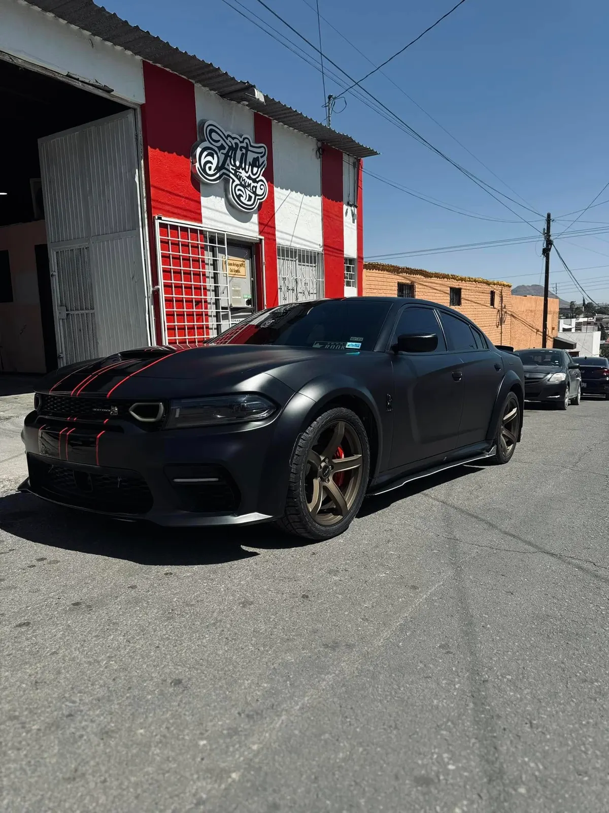 Dodge Charger con wrap negro mate frente al taller