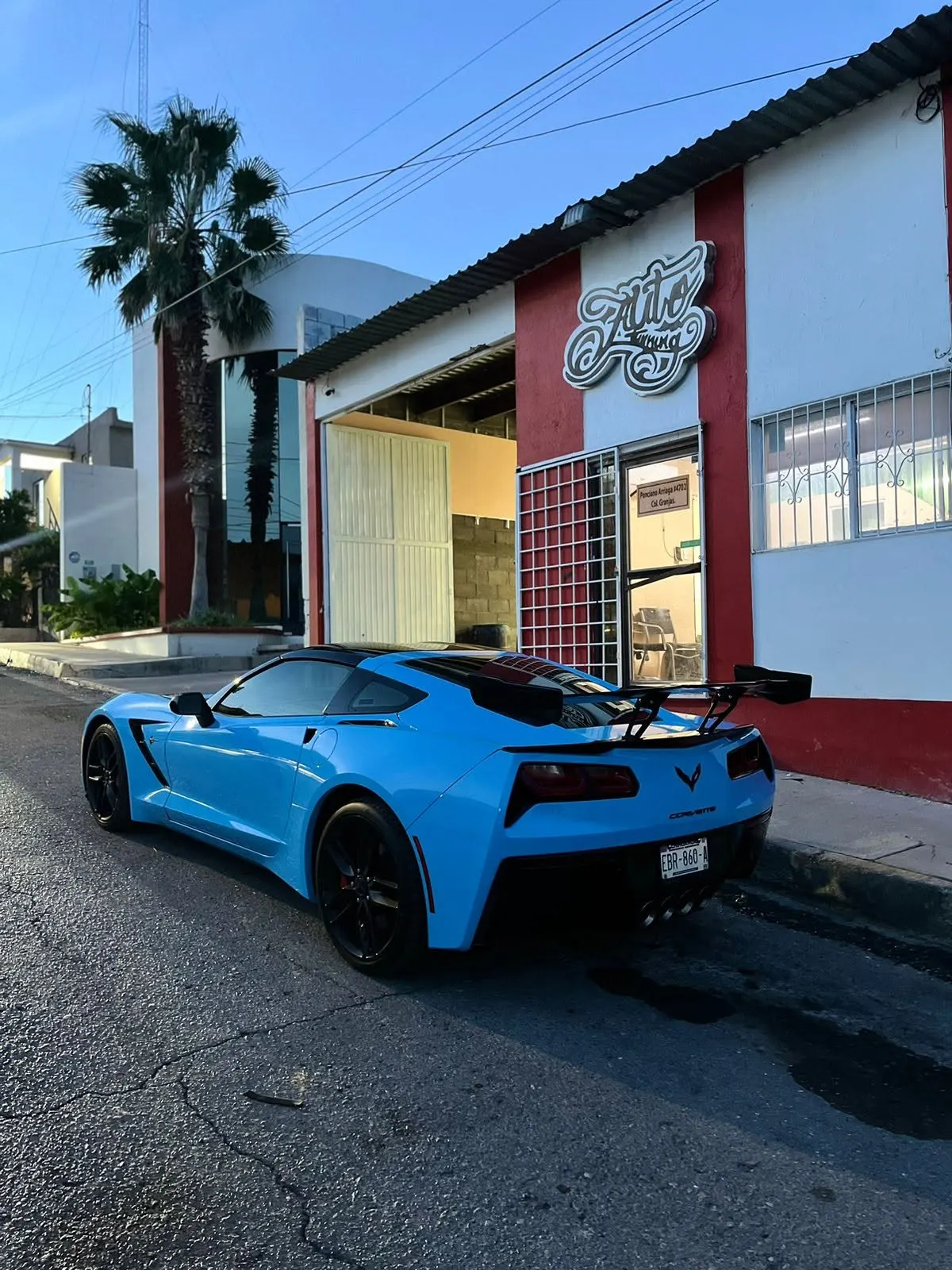 Chevrolet Corvette con wrap azul frente al taller