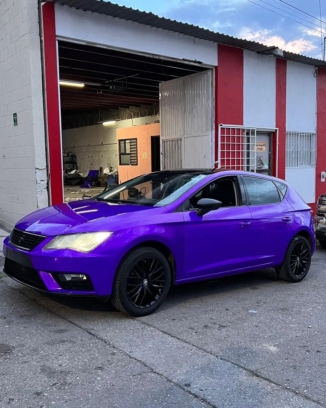 Seat León con wrap morado frente al taller